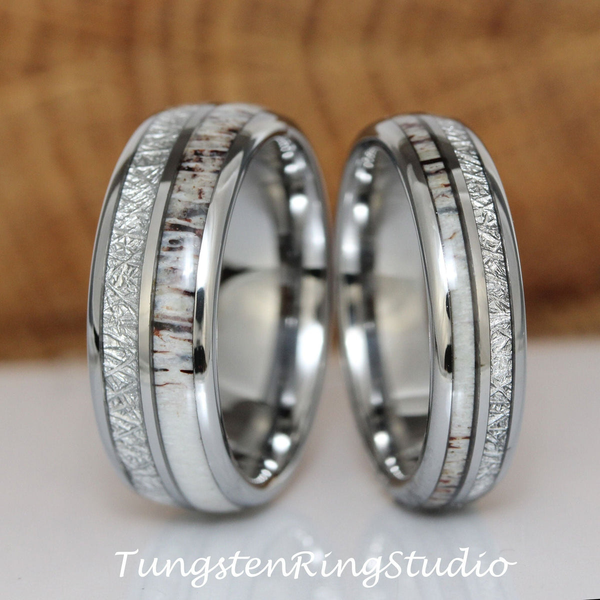 May include: Two silver tungsten carbide wedding bands with a white and brown antler inlay. The bands have a brushed finish and a beveled edge.