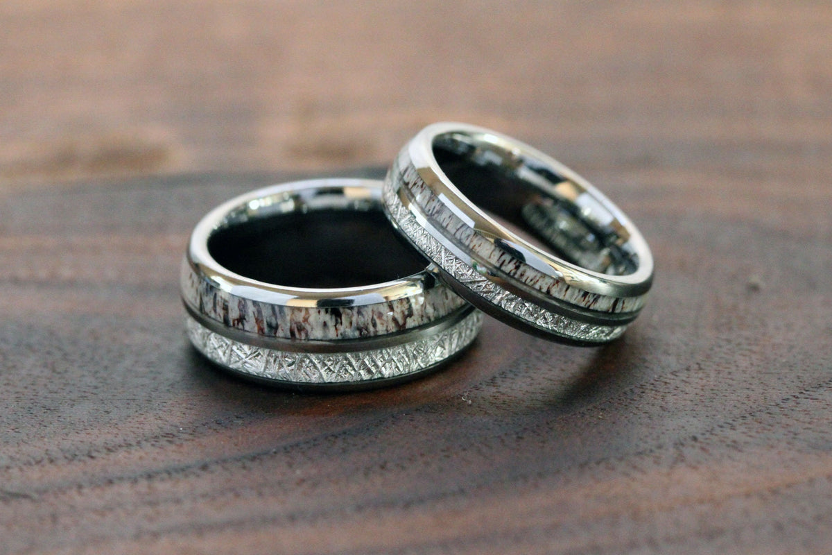 May include: Two silver wedding bands with a white and black inlay design.