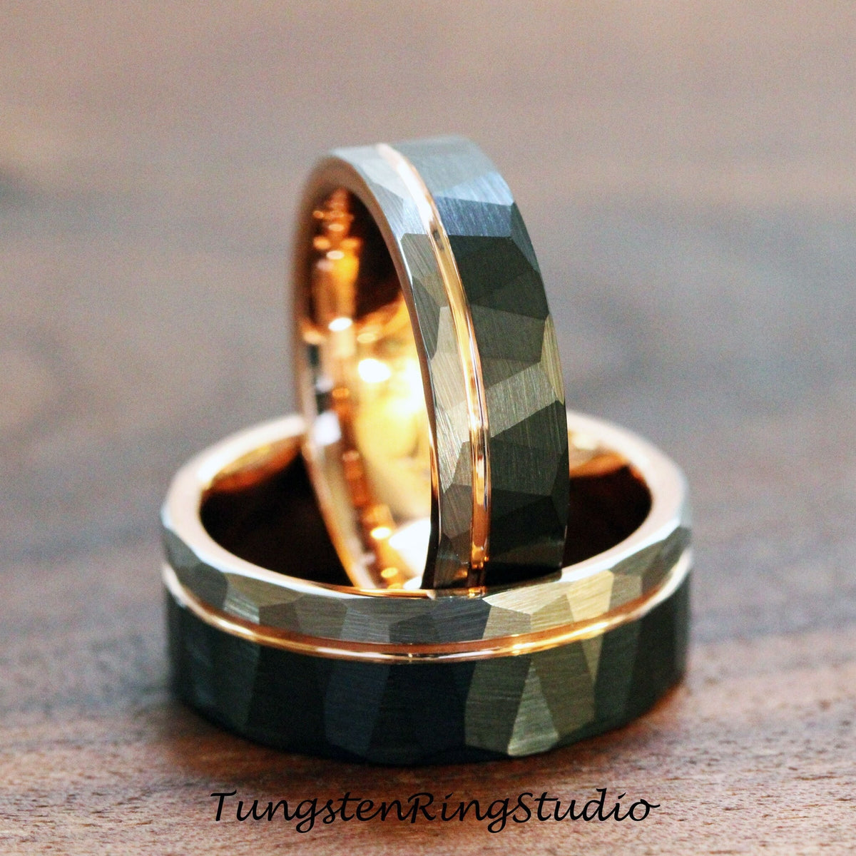 May include: Two tungsten carbide wedding bands with a hammered finish and a rose gold inlay. The bands are stacked on top of each other.