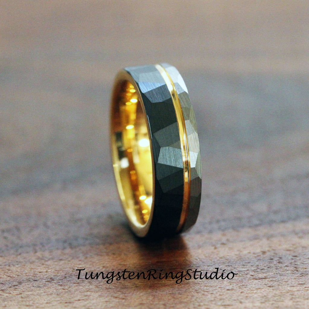 May include: A black tungsten carbide ring with a gold band. The ring has a hammered finish and a beveled edge.