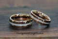 May include: Two wedding rings with a gold band, a dark wood inlay, and a white opal center. The rings are displayed on a wooden surface. The text "TungstenRingStudio" is visible at the bottom.