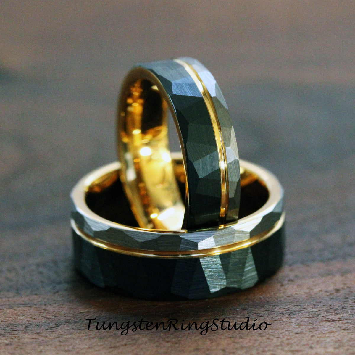 May include: Two tungsten carbide rings with a gold inlay. The rings have a hammered finish and a beveled edge.
