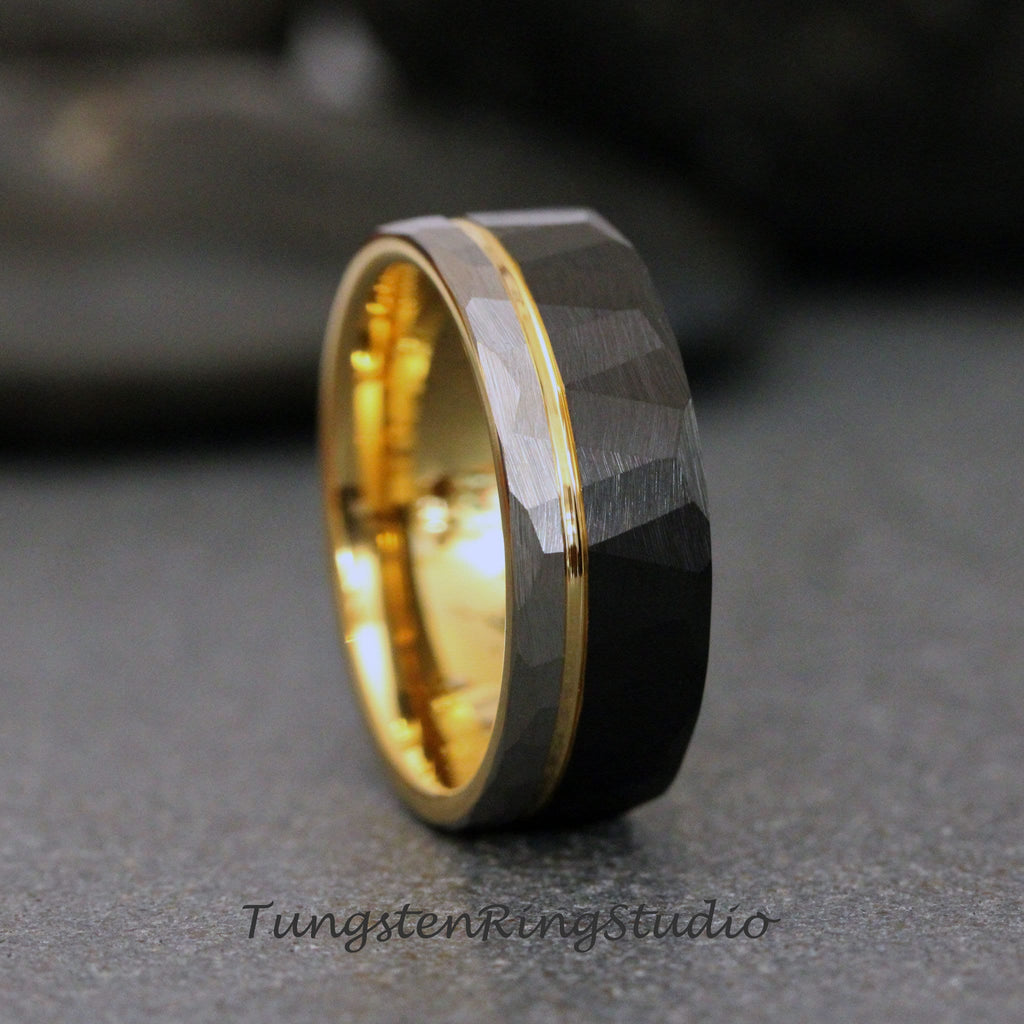 May include: A black tungsten carbide ring with a gold band. The ring has a hammered finish and a beveled edge.