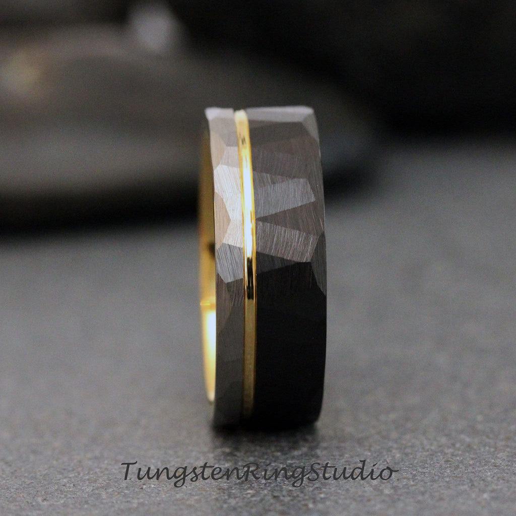 May include: A black tungsten carbide ring with a gold inlay. The ring has a hammered finish and a beveled edge.