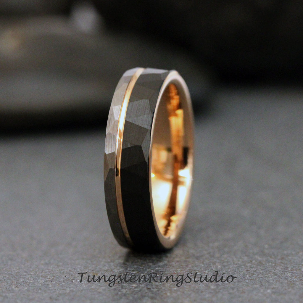 May include: A black tungsten carbide ring with a rose gold band. The ring has a hammered finish and a beveled edge.