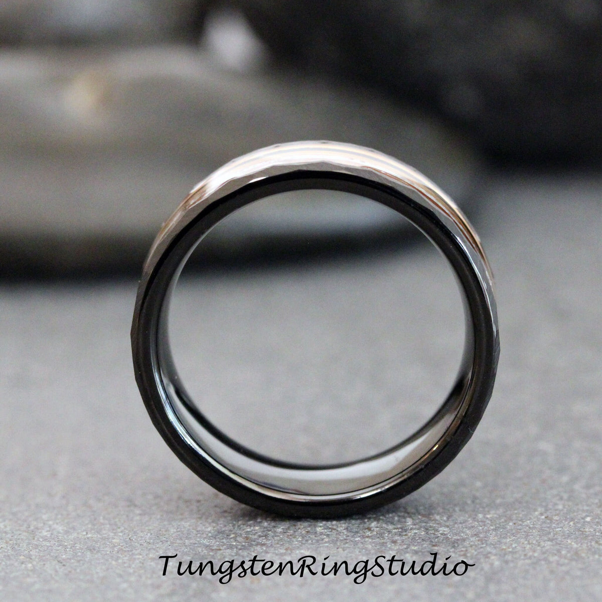 May include: A black tungsten carbide ring with a silver band around the outside edge.