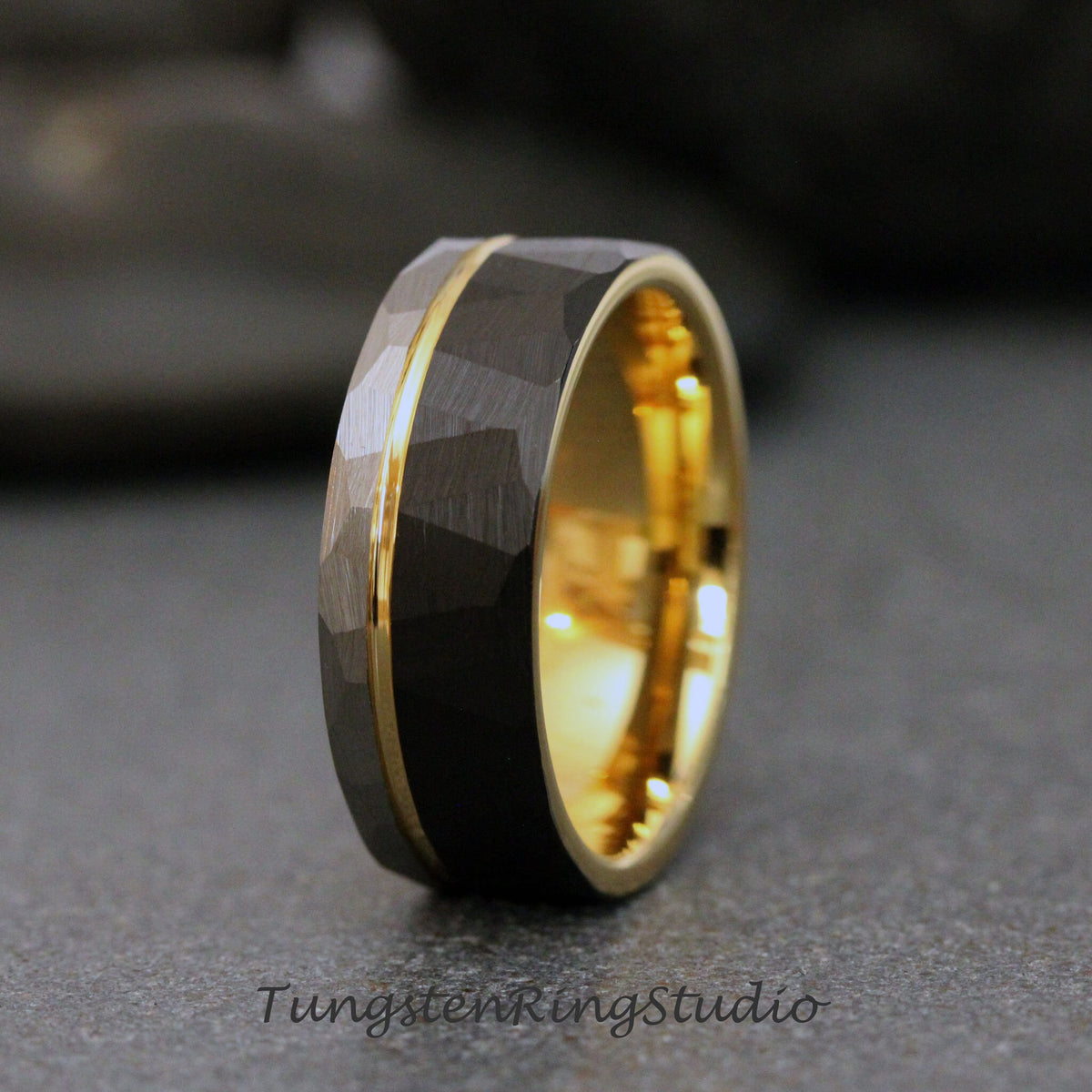 May include: A black tungsten carbide ring with a gold band. The ring has a hammered finish.