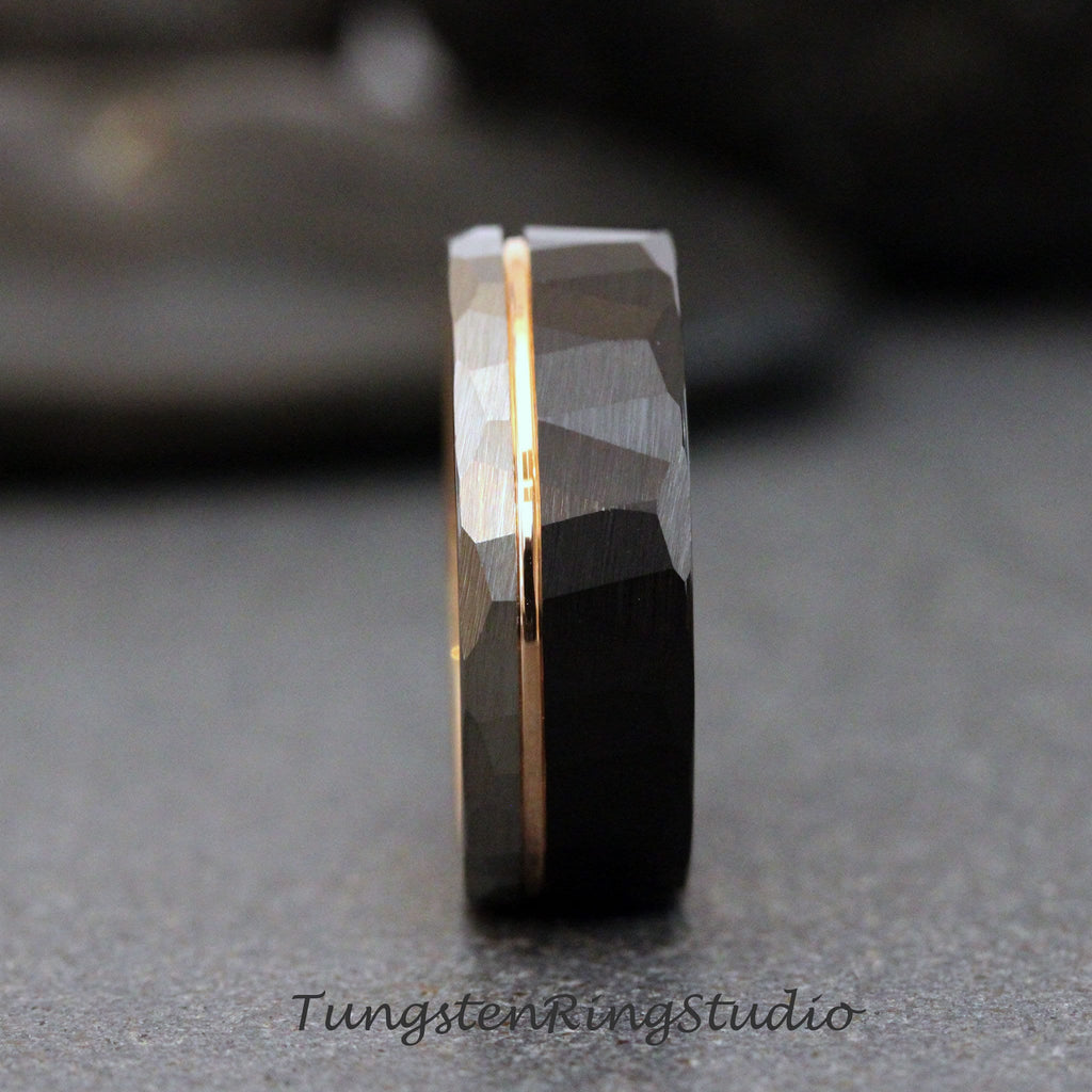May include: A black tungsten carbide ring with a rose gold inlay. The ring has a hammered finish and a beveled edge.