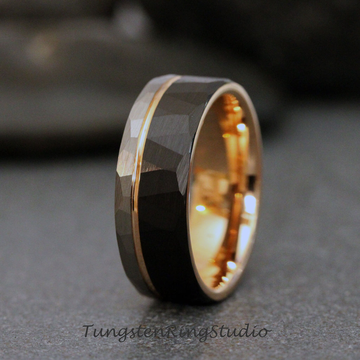 May include: A black tungsten carbide ring with a rose gold band and a hammered finish.