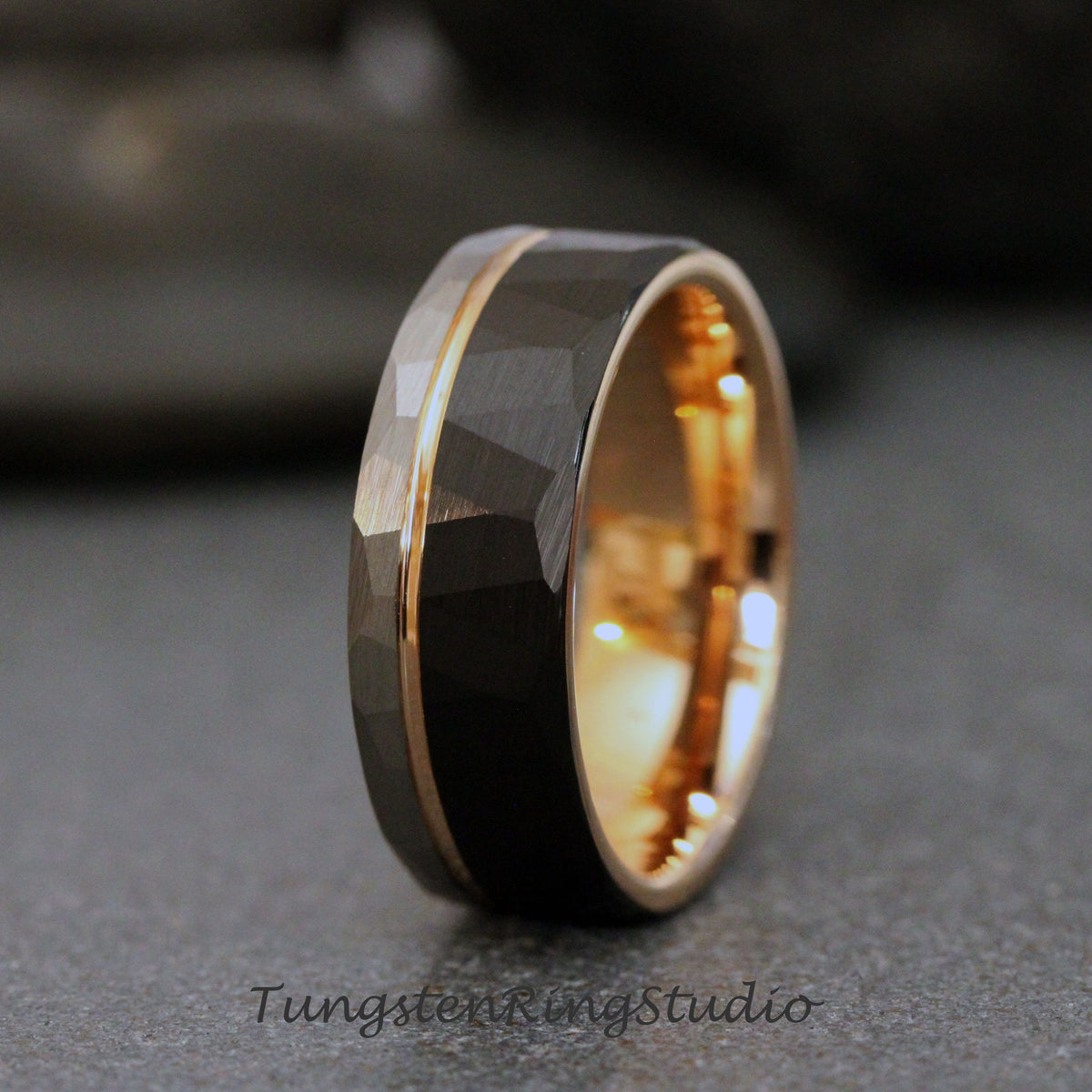 May include: A black tungsten carbide ring with a rose gold band and a hammered finish.