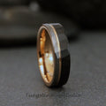 May include: A black tungsten carbide ring with a rose gold inlay. The ring has a hammered finish.