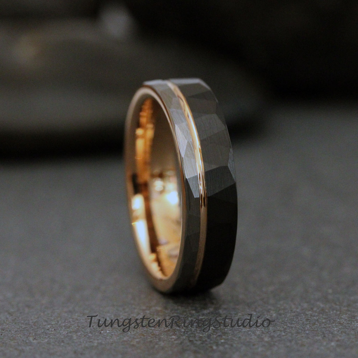 May include: A black tungsten carbide ring with a rose gold inlay. The ring has a hammered finish.