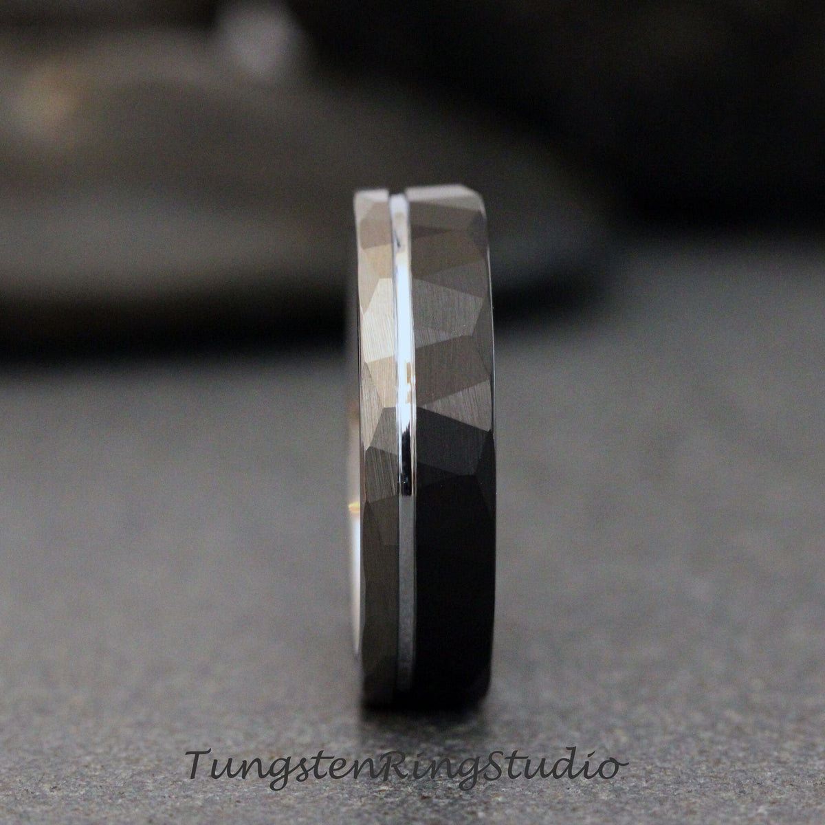 May include: A black tungsten carbide ring with a silver band and a hammered finish.