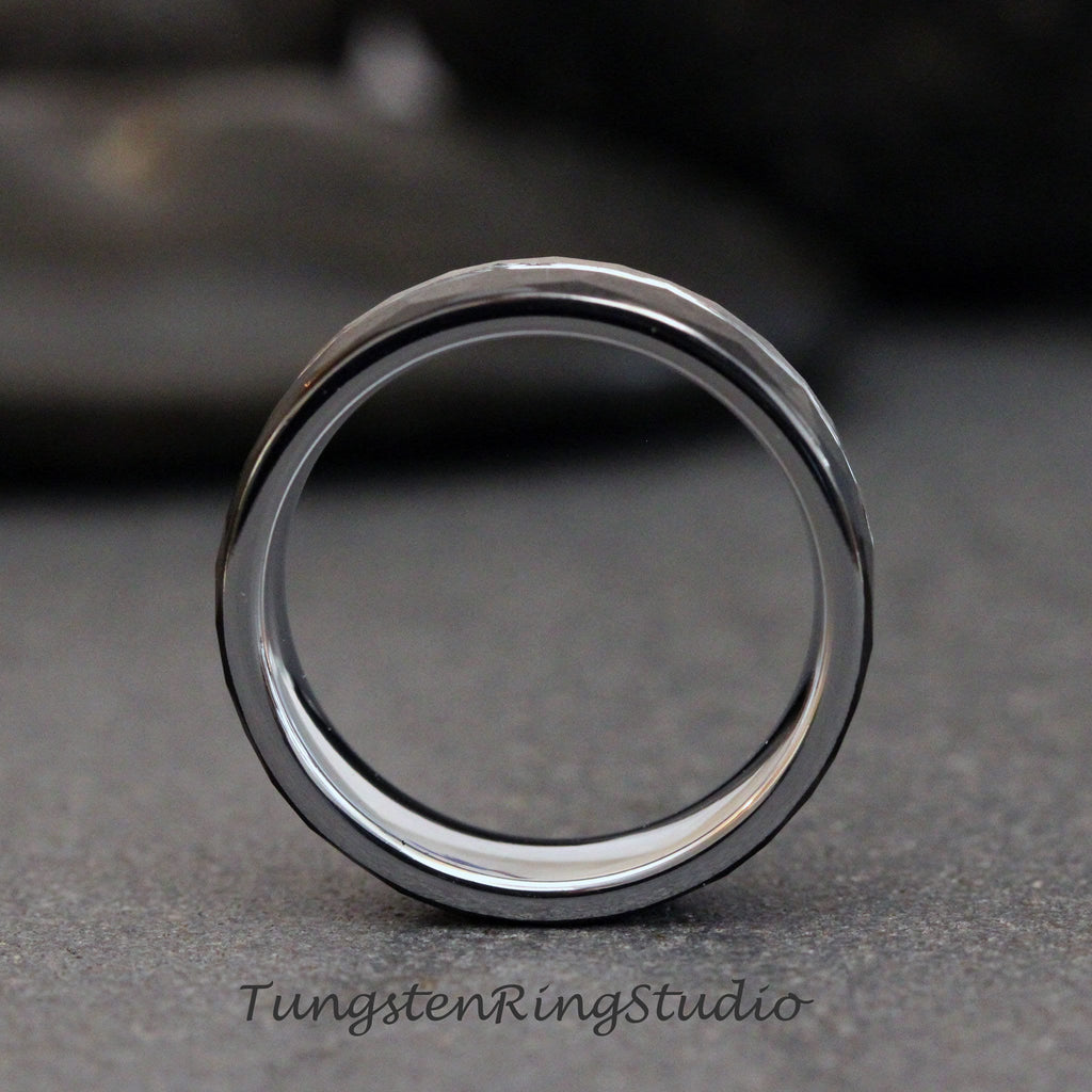May include: A silver tungsten carbide ring with a hammered finish. The ring is shown from the side, with the inside of the ring facing the viewer.