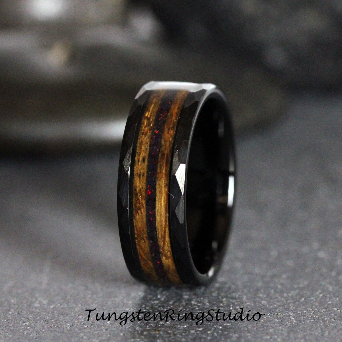 May include: Black tungsten carbide ring with a wood inlay and red glitter accents. The ring has a beveled edge.