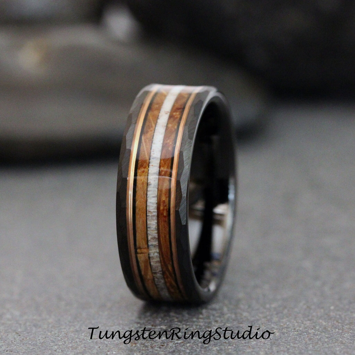 May include: A black tungsten ring with a hammered finish and a band of wood, bone, and copper inlay.