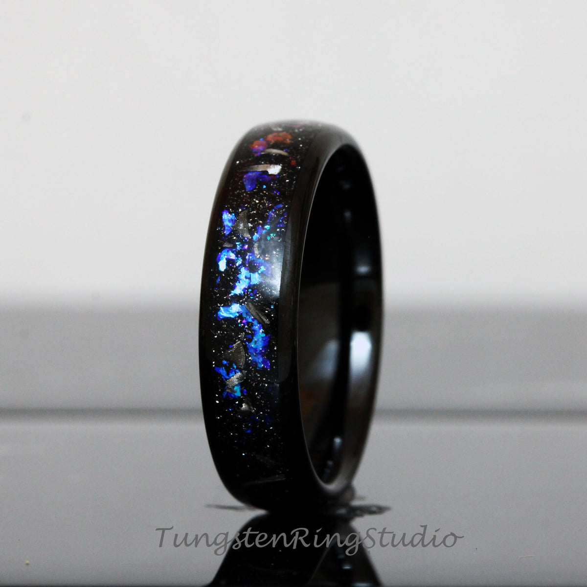 May include: A black tungsten carbide ring with a blue and silver glitter inlay. The ring is polished and has a high shine.