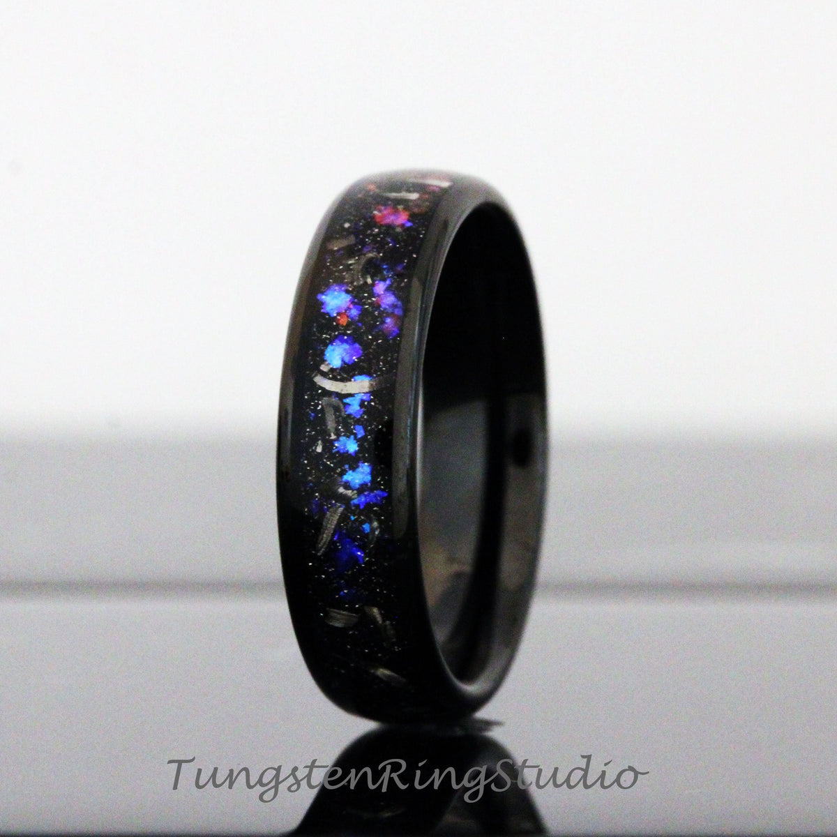 May include: Black tungsten carbide ring with a blue, pink, and silver glitter inlay.