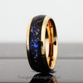 May include: A black and blue tungsten carbide ring with a rose gold band. The ring has a unique design with blue and black flecks throughout the band.