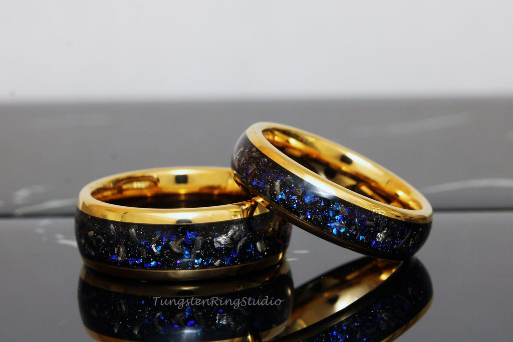May include: Two gold tungsten carbide rings with a blue and black inlay. The rings have a gold band around the edge.