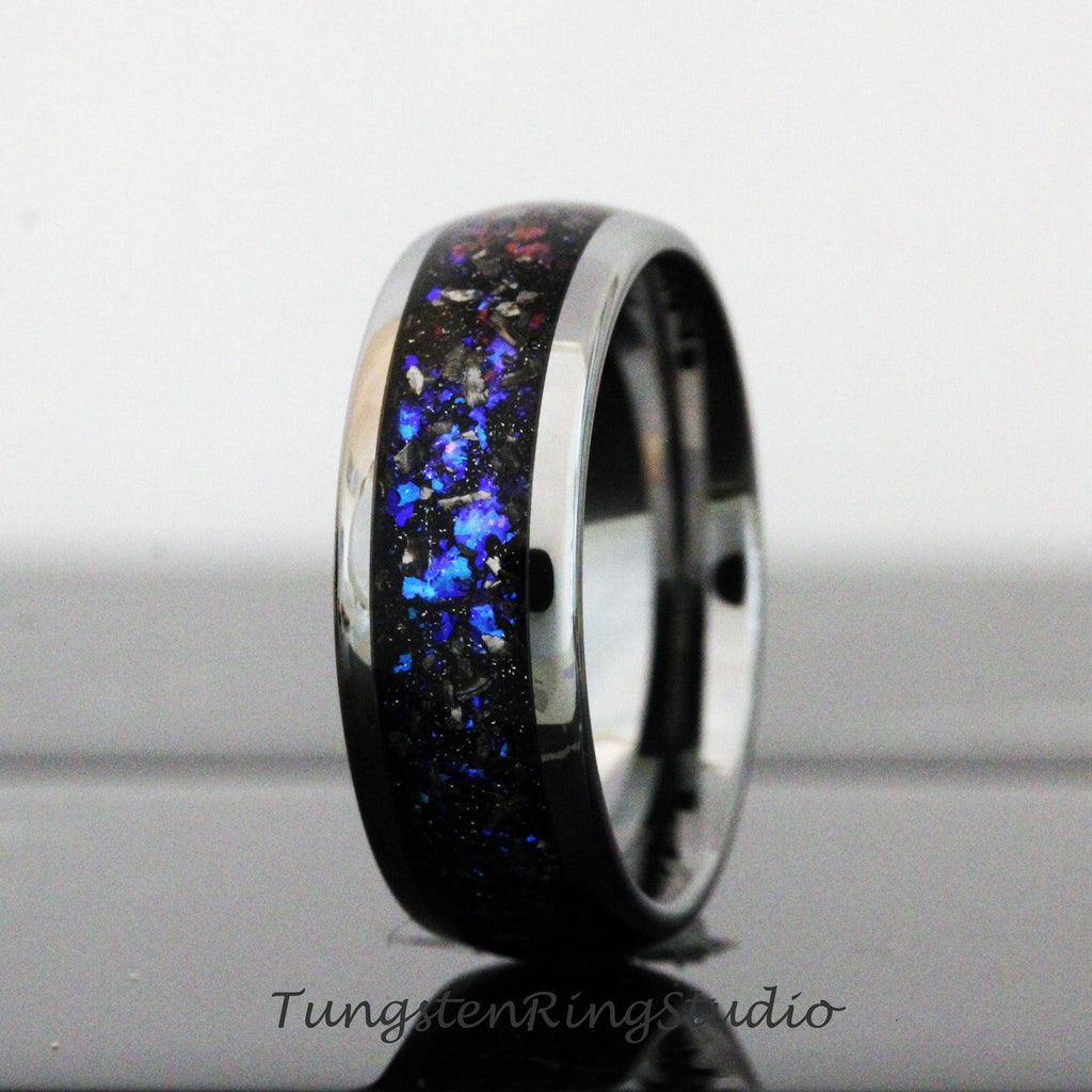 May include: A black tungsten carbide ring with a blue and silver inlay. The ring has a polished finish and a beveled edge.