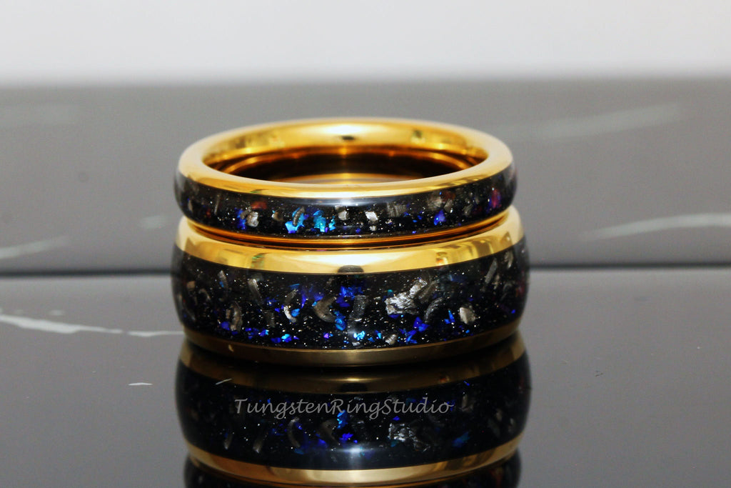 May include: Two gold tungsten carbide rings with a black and blue inlay. The rings are stacked on top of each other.