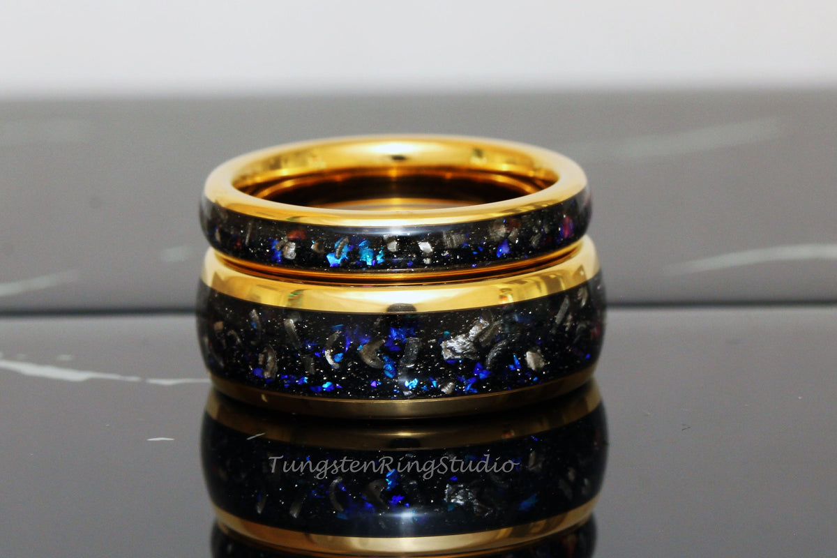May include: Two gold tungsten carbide rings with a black and blue inlay. The rings are stacked on top of each other.