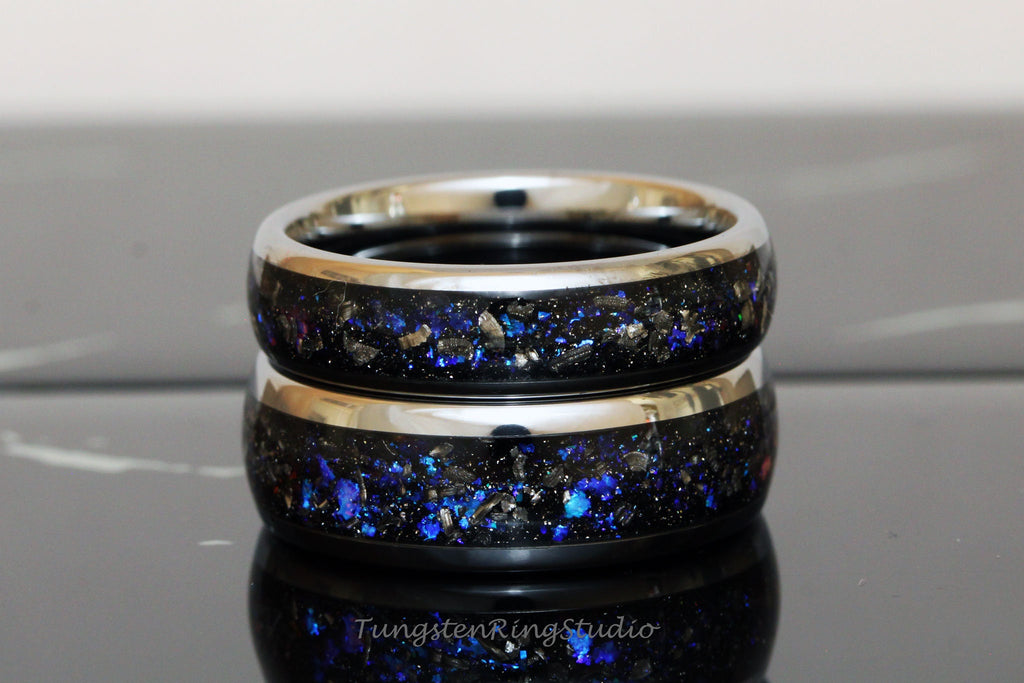 May include: Two stacked tungsten carbide rings with a black and blue galaxy-inspired design. The rings have a silver-colored band.