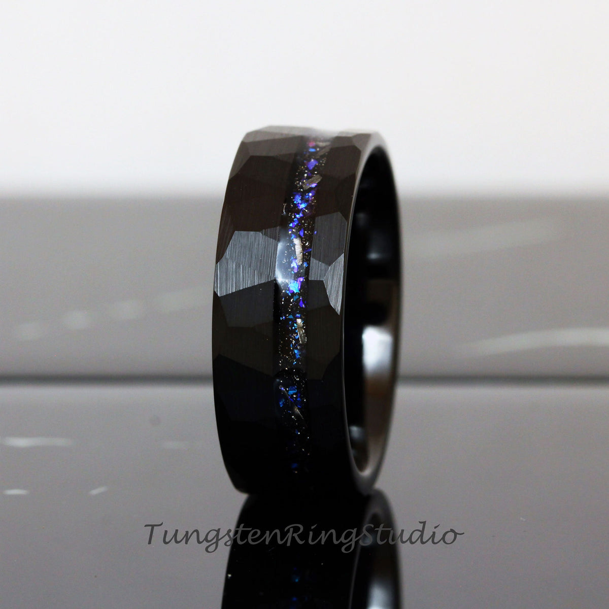 May include: Black tungsten carbide ring with a hammered finish and a blue and silver glitter inlay.