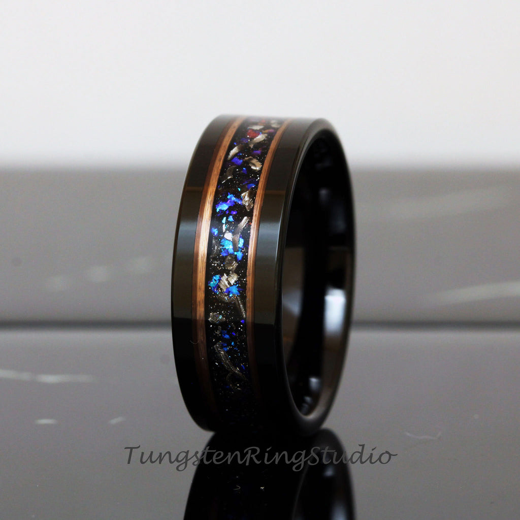 May include: A black tungsten ring with a copper and blue inlay. The inlay features a scattered pattern of blue and copper flecks.