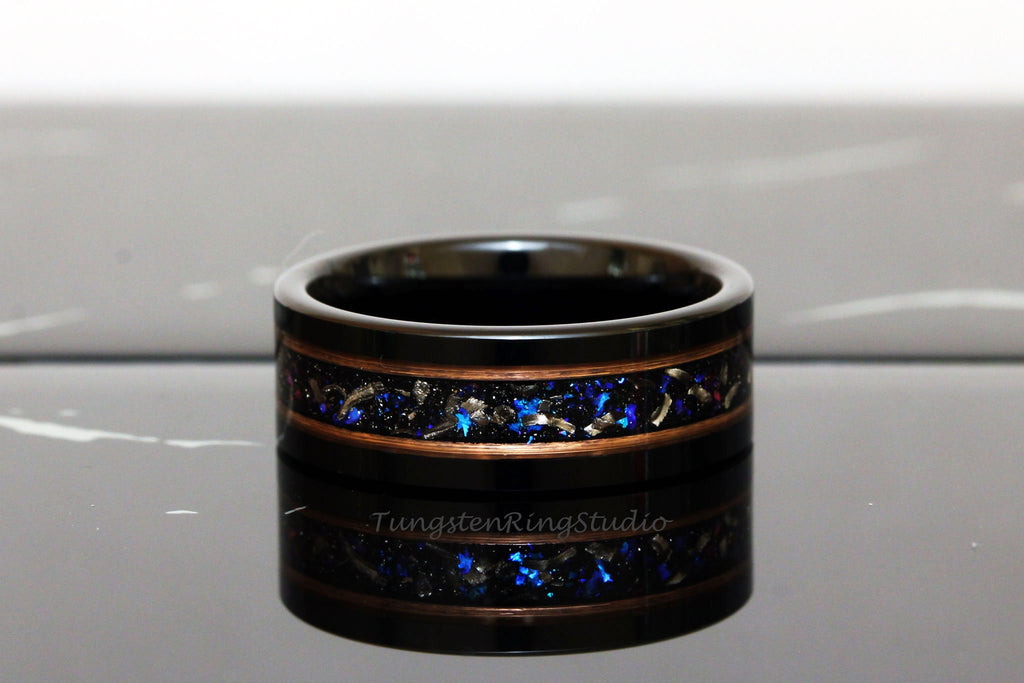 May include: Black tungsten ring with a copper inlay and blue and silver glitter. The ring is on a reflective surface. TungstenRingsStudio is visible on the ring.