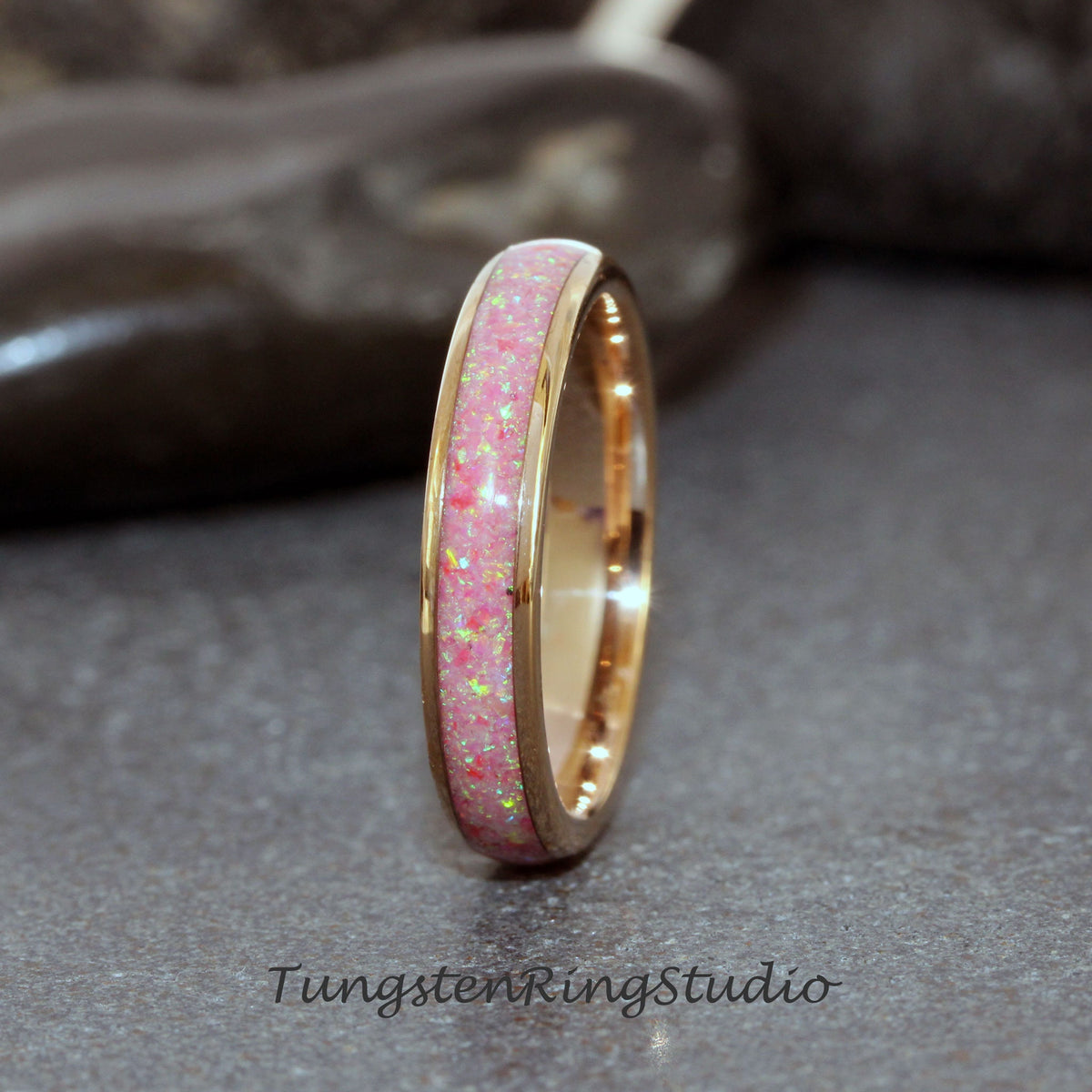 May include: A thin gold band with a pink opal inlay. The band is smooth and polished, and the opal inlay is sparkly and eye-catching.