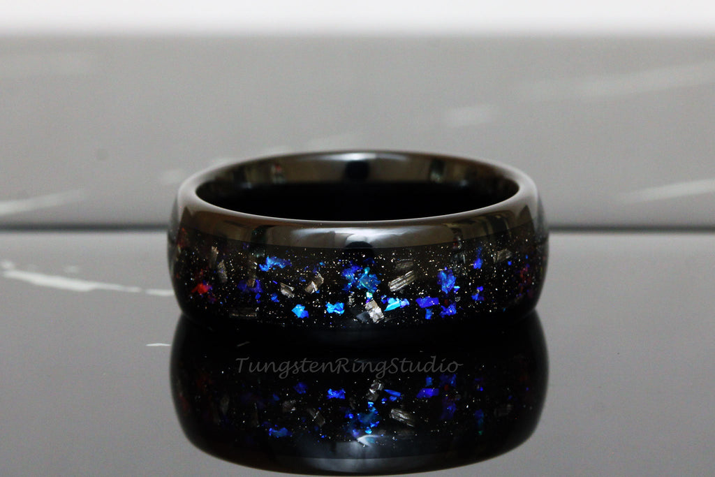 May include: Black tungsten ring with blue and silver glitter embedded in the band. The ring is polished and has a high shine.