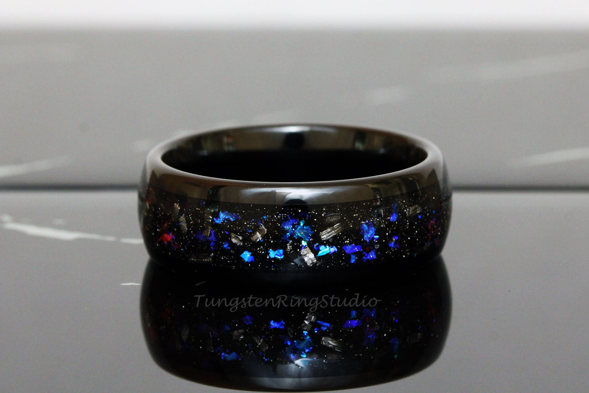 May include: Black tungsten ring with blue and silver glitter embedded in the band. The ring is polished and has a high shine.