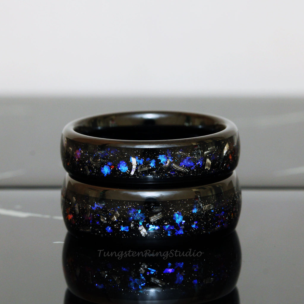 May include: Two black tungsten carbide rings with blue and silver glitter embedded in the black resin. The rings are stacked on top of each other.