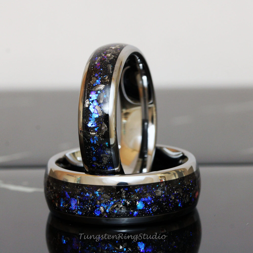 May include: Two black tungsten carbide rings with a silver band and blue and silver glitter embedded in the black surface. The rings are stacked on top of each other.