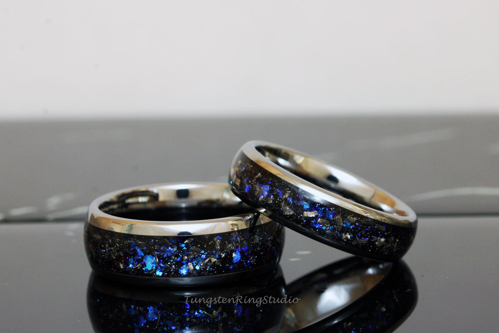 May include: Two silver tungsten carbide rings with a black inlay and blue glitter. The rings are stacked on top of each other.
