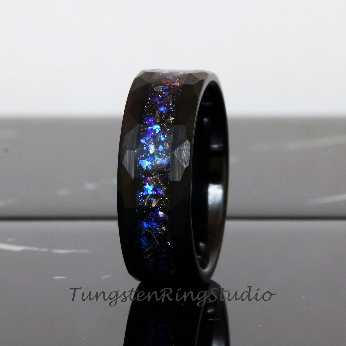 May include: Black tungsten carbide ring with a blue and silver glitter inlay. The ring has a beveled edge and a brushed finish.