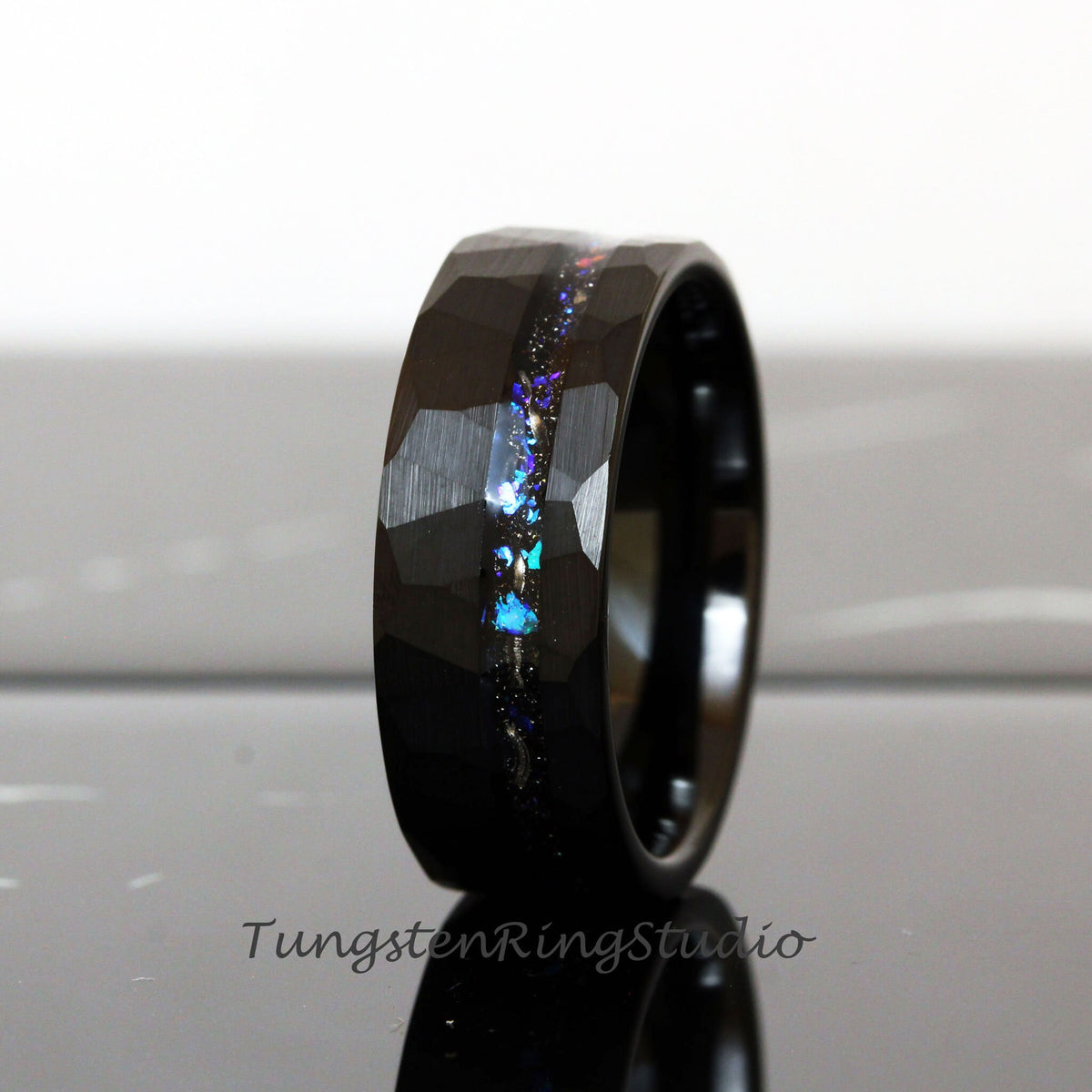 May include: Black tungsten carbide ring with a hammered finish and a thin line of iridescent glitter embedded in the band.