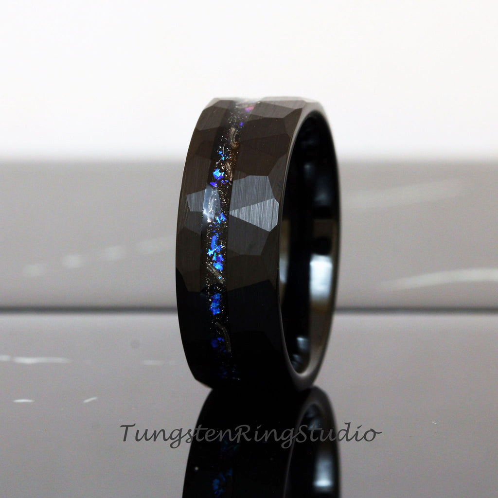 May include: Black tungsten carbide ring with a hammered finish and a blue and silver inlay. The ring is approximately 8mm wide.