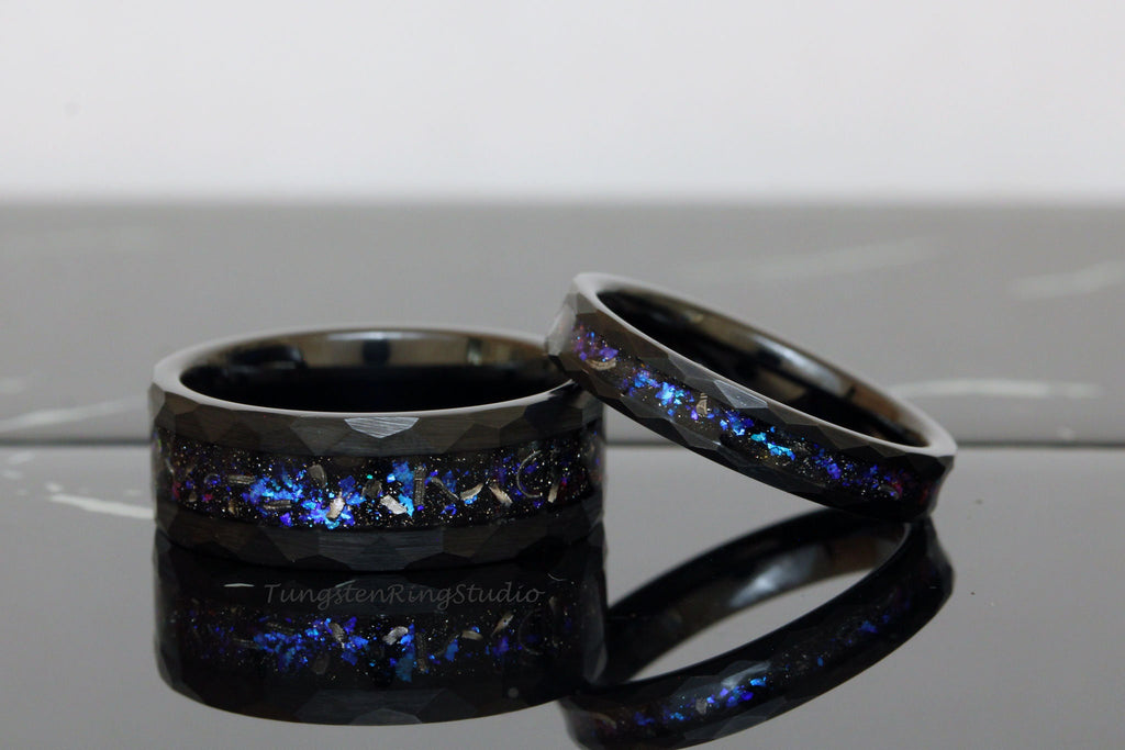 May include: Two black tungsten carbide rings with a blue and purple glitter inlay. The rings have a beveled edge and a brushed finish.