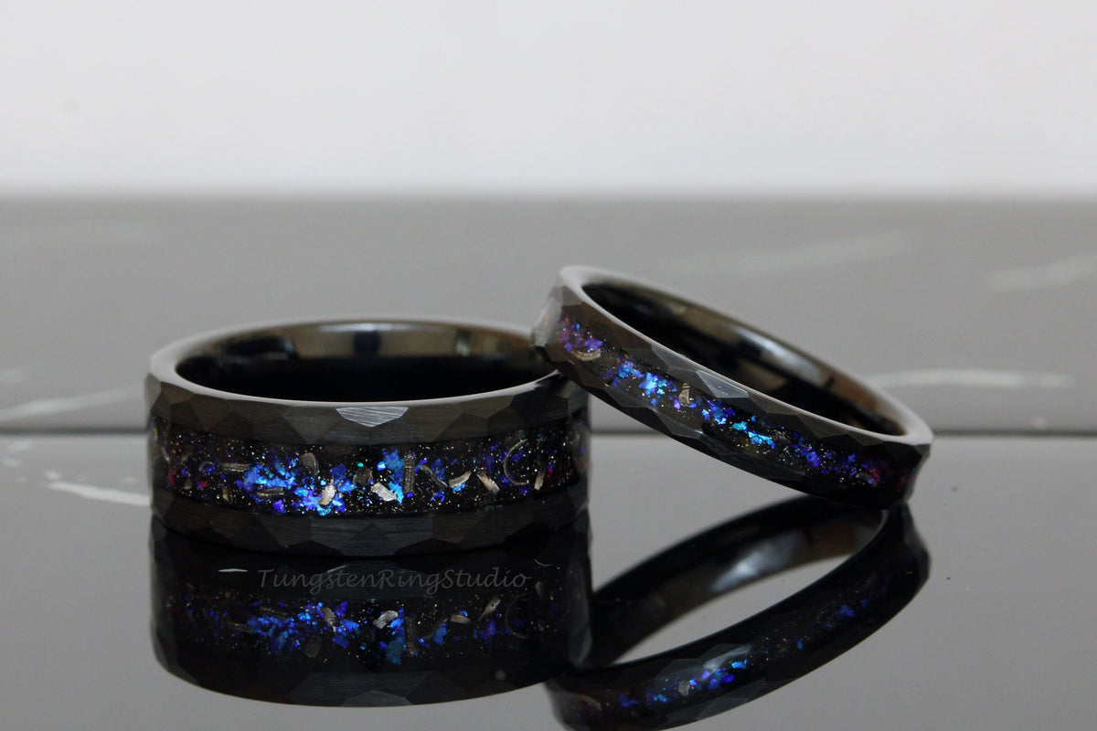May include: Two black tungsten carbide rings with a blue and purple glitter inlay. The rings have a beveled edge and a brushed finish.