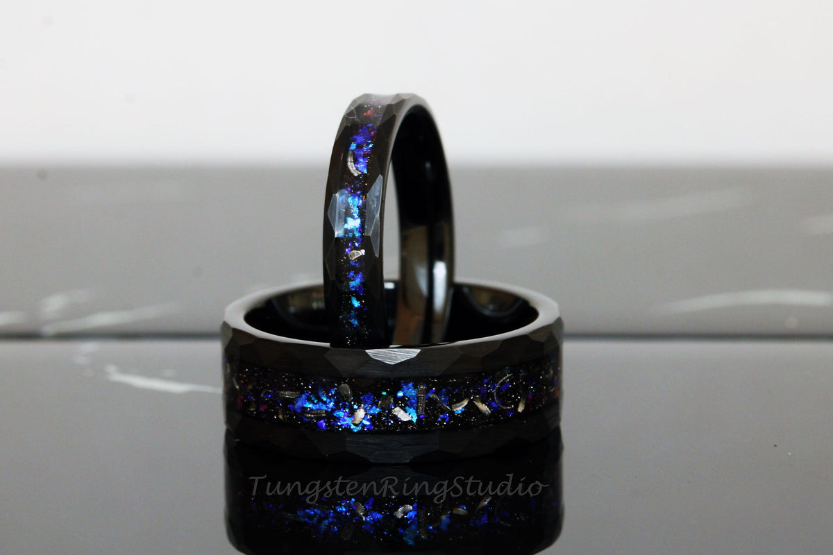 May include: Two black tungsten carbide rings with a blue and silver glitter inlay. The rings are stacked on top of each other.