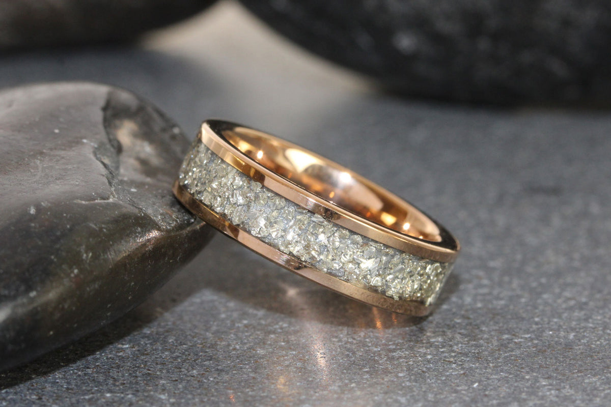 May include: A rose gold wedding band with a band of embedded silver glitter.