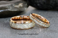 May include: Two rose gold tungsten carbide wedding bands with a row of small, clear, faceted stones set into the band.