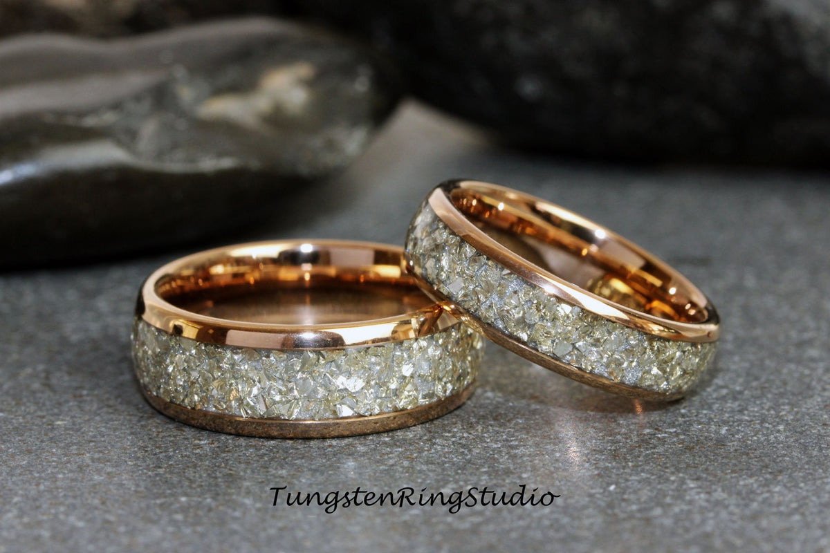 May include: Two rose gold tungsten carbide rings with a band of small, clear diamonds.
