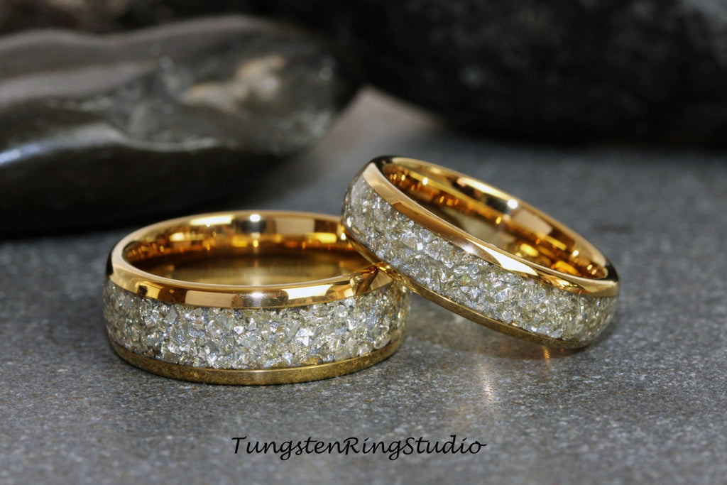 May include: Two gold tungsten carbide rings with a band of white diamond-like particles. The rings are stacked on top of each other.