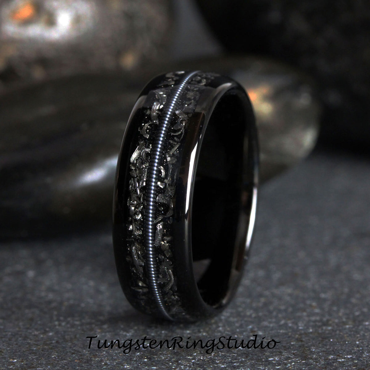 May include: A black tungsten carbide ring with a silver inlay design. The ring has a polished finish and a comfortable fit.