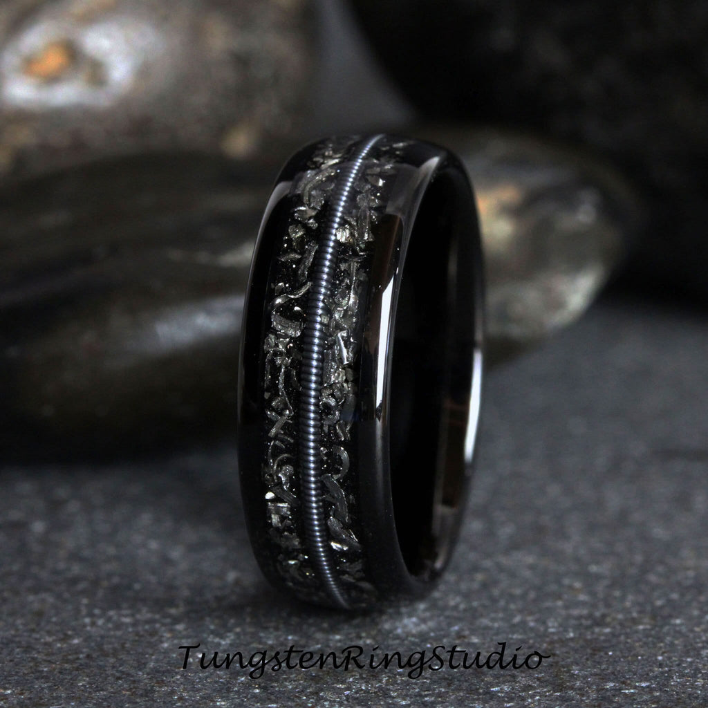 May include: A black tungsten carbide ring with a silver inlay design. The ring has a polished finish and a comfortable fit.