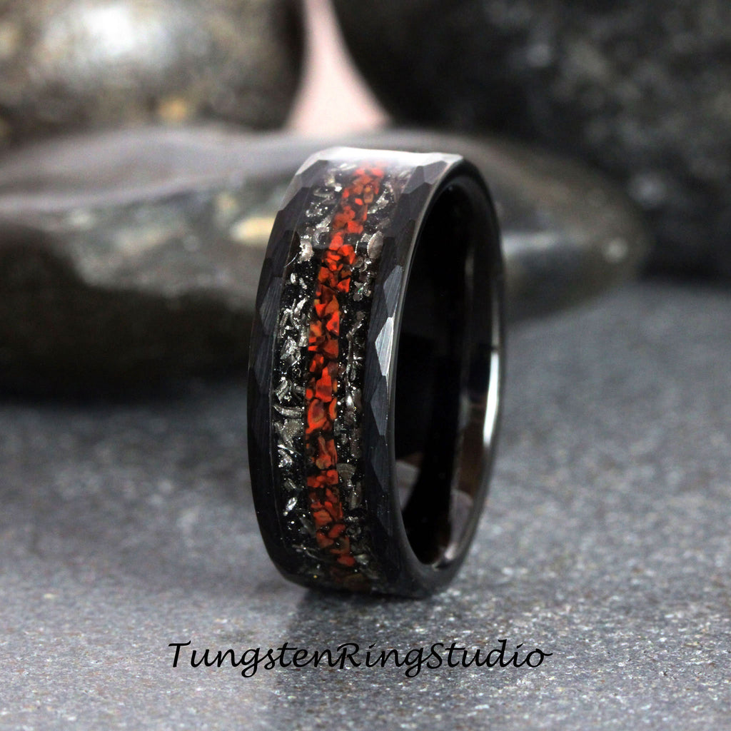 May include: Black tungsten carbide ring with a hammered finish and a red and silver inlay. Tungsten Ring Studio.